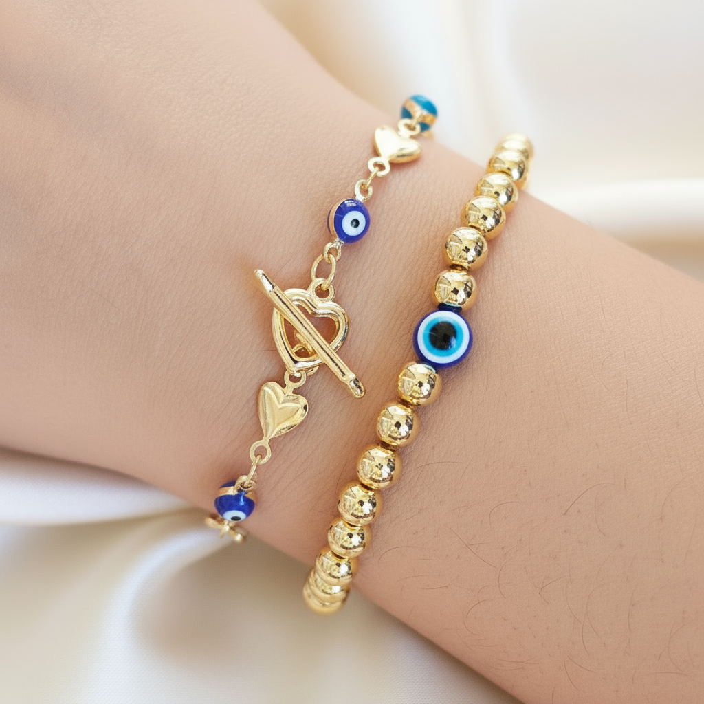 Gold bracelet with blue evil eye charms on a wrist against a soft pink background