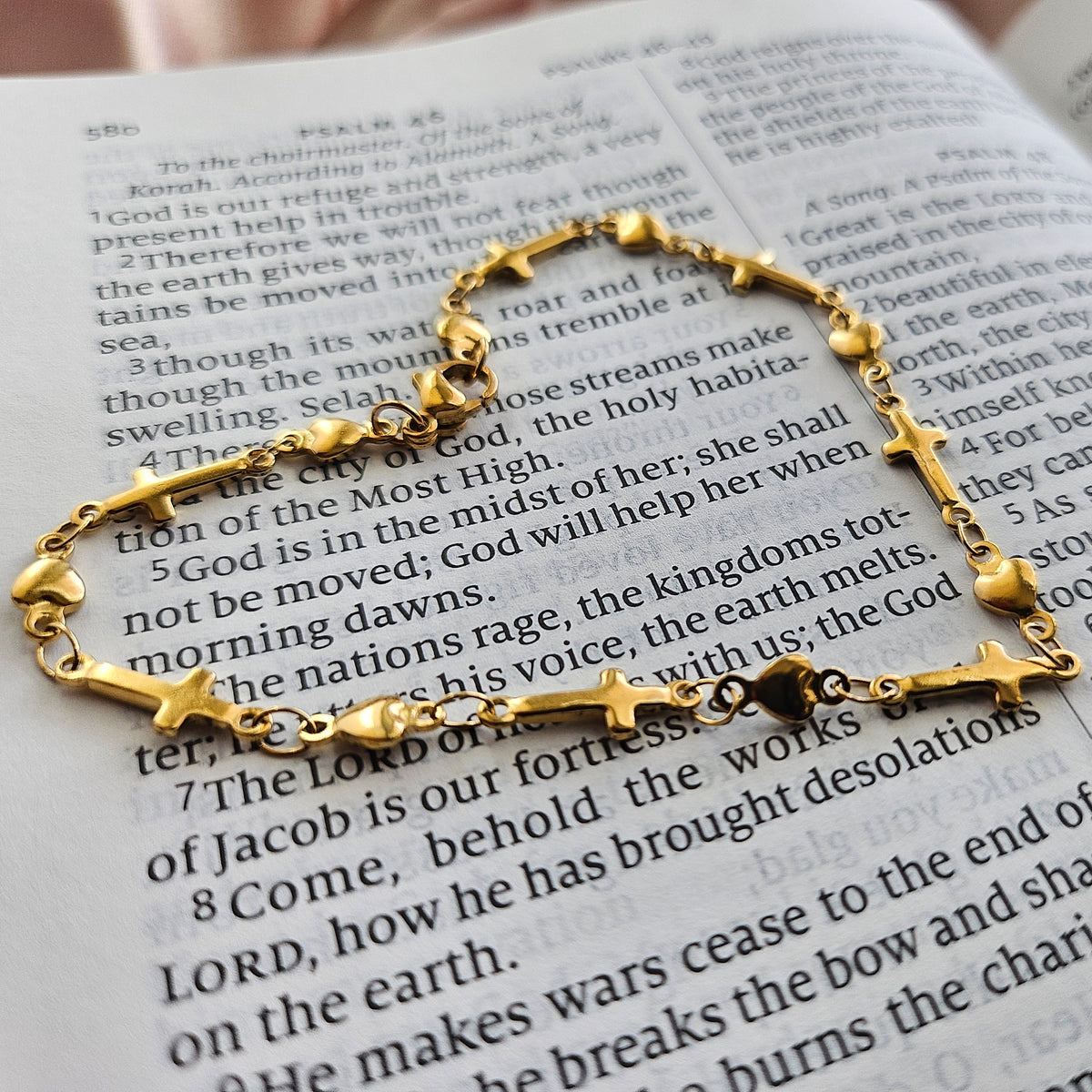 Gold bracelet with star and cross designs on an open book