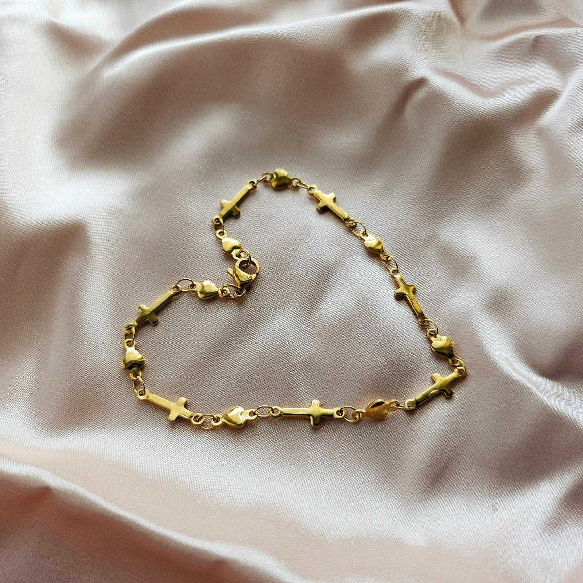 Gold bracelet with cross designs on a beige fabric background