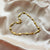 Gold bracelet with cross designs on a beige fabric background